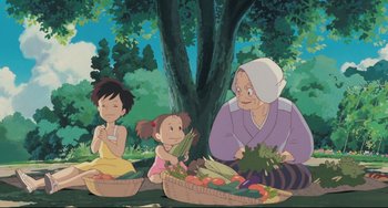 Movie still from “My Neighbor Totoro” (1988), directed by Hayao Miyazaki – A group of people sitting under a tree with baskets of vegetables; Medium shot, Low angle