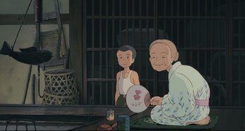Movie still from “My Neighbor Totoro” (1988), directed by Hayao Miyazaki – A man and a boy sitting in front of a building; Medium shot, Low angle