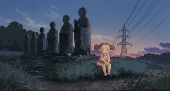 Movie still from “My Neighbor Totoro” (1988), directed by Hayao Miyazaki – An animated scene of a girl sitting in front of a group of statues; Extreme Wide shot, Low angle
