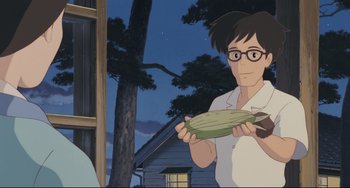 Movie still from “My Neighbor Totoro” (1988), directed by Hayao Miyazaki – An animated person holding a piece of food in front of a house; Medium shot, Low angle
