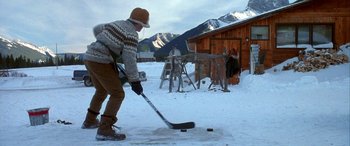 Movie still from “Mystery, Alaska” (1999), directed by Jay Roach – A man playing hockey outside in the snow; Wide shot, High angle