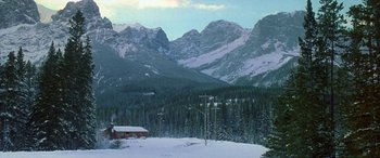 Movie still from “Mystery, Alaska” (1999), directed by Jay Roach – A mountain range with a house and power lines in the foreground; Extreme Wide shot, High angle