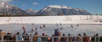 Movie still from “Mystery, Alaska” (1999), directed by Jay Roach – A group of people playing a game of ice hockey on a frozen lake; Extreme Wide shot, High angle