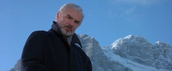 Movie still from “Mystery, Alaska” (1999), directed by Jay Roach – An older man in a black jacket is in front of a snowy mountain; Close Up shot, Low angle