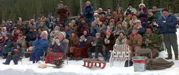 Movie still from “Mystery, Alaska” (1999), directed by Jay Roach – A group of people sitting in the snow with sleds; Wide shot, High angle