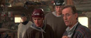 Movie still from “Mystery, Alaska” (1999), directed by Jay Roach – A group of men standing next to each other in a room; Medium shot, Over the shoulder angle