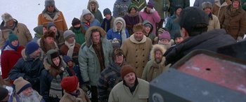 Movie still from “Mystery, Alaska” (1999), directed by Jay Roach – A large group of people wearing winter coats and hats; Wide shot, High angle