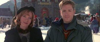 Movie still from “Mystery, Alaska” (1999), directed by Jay Roach – A man and a woman standing next to each other in front of a building; Medium shot, Over the shoulder angle