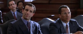 A man in a suit sitting next to another man in a suit