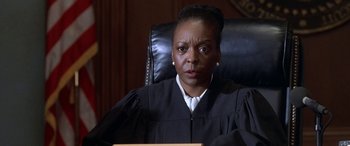 Movie still from “Mystery, Alaska” (1999), directed by Jay Roach – A judge sitting in a chair in front of a judge's chair; Close Up shot, High angle