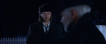 Movie still from “Mystery, Alaska” (1999), directed by Jay Roach – A man in a suit and a man in a hat; Medium shot, Over the shoulder angle