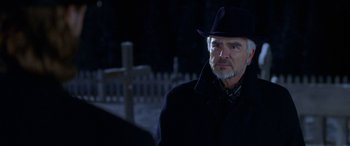Movie still from “Mystery, Alaska” (1999), directed by Jay Roach – A man in a black hat and a black coat; Close Up shot, Over the shoulder angle