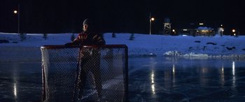 Movie still from “Mystery, Alaska” (1999), directed by Jay Roach – A man standing on a hockey rink at night; Wide shot, High angle