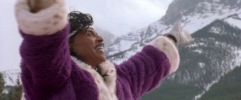 Movie still from “Mystery, Alaska” (1999), directed by Jay Roach – A woman in a purple coat is standing in front of a snowy mountain; Close Up shot, Low angle