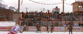 Movie still from “Mystery, Alaska” (1999), directed by Jay Roach – A group of men playing a game of ice hockey on a rink; Extreme Wide shot, High angle