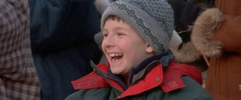 Movie still from “Mystery, Alaska” (1999), directed by Jay Roach – A young boy wearing a winter hat and jacket smiling; Close Up shot, Low angle