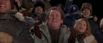 Movie still from “Mystery, Alaska” (1999), directed by Jay Roach – A group of people that are sitting in a crowd; Medium shot, Over the shoulder angle
