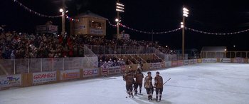 Movie still from “Mystery, Alaska” (1999), directed by Jay Roach – A group of men standing next to each other on the ice; Extreme Wide shot, High angle
