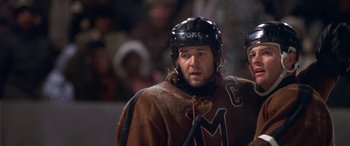 Movie still from “Mystery, Alaska” (1999), directed by Jay Roach – A hockey player wearing a brown jacket and a black helmet; Close Up shot, Low angle