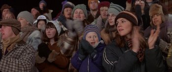 Movie still from “Mystery, Alaska” (1999), directed by Jay Roach – A group of people standing in a crowd wearing winter hats; Medium shot, Over the shoulder angle