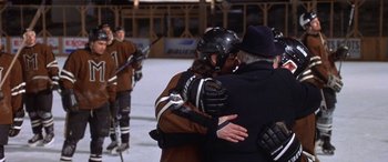 Movie still from “Mystery, Alaska” (1999), directed by Jay Roach – A couple of people that are hugging on the ice; Medium shot, Over the shoulder angle