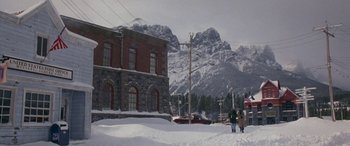 Movie still from “Mystery, Alaska” (1999), directed by Jay Roach – Two people walking in the snow in front of a building; Extreme Wide shot, Low angle