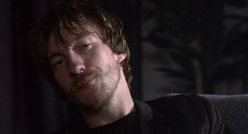 Movie still from “Naked” (1993), directed by Mike Leigh – A person wearing a black shirt; Close Up shot, Over the shoulder angle