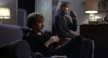 Movie still from “Naked” (1993), directed by Mike Leigh – Two men sitting on a couch smoking and drinking; Medium shot, High angle