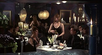 Movie still from “Naked” (1993), directed by Mike Leigh – A group of people sitting at a table with candles; Medium shot, Over the shoulder angle