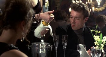 Movie still from “Naked” (1993), directed by Mike Leigh – A man pouring champagne into a wine glass at a party; Close Up shot, Over the shoulder angle