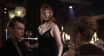 Movie still from “Naked” (1993), directed by Mike Leigh – A woman holding a tray of food and a glass of wine; Medium shot, Over the shoulder angle