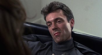 Movie still from “Naked” (1993), directed by Mike Leigh – A person sitting in a chair wearing a sweater; Close Up shot, Low angle