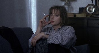 Movie still from “Naked” (1993), directed by Mike Leigh – A woman smoking a cigarette while sitting on a chair; Close Up shot, High angle