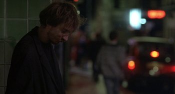 Movie still from “Naked” (1993), directed by Mike Leigh – A man standing on a street at night with his eyes closed; Close Up shot, Over the shoulder angle