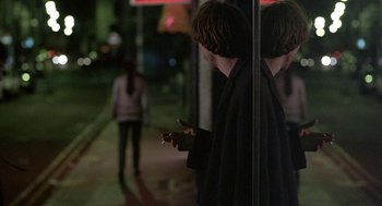 Movie still from “Naked” (1993), directed by Mike Leigh – A woman smoking a cigarette in front of a store window; Medium shot, Over the shoulder angle