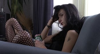 Movie still from “Naked” (1993), directed by Mike Leigh – A woman sitting on a couch holding a can of beer; Close Up shot, High angle
