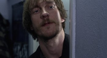 Movie still from “Naked” (1993), directed by Mike Leigh – A person with a beard and mustache; Close Up shot, Over the shoulder angle