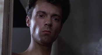 Movie still from “Naked” (1993), directed by Mike Leigh – A man's face in a dark room; Close Up shot, Low angle