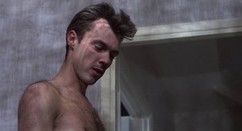 Movie still from “Naked” (1993), directed by Mike Leigh – A man with a beard is standing in a bathroom; Close Up shot, Low angle