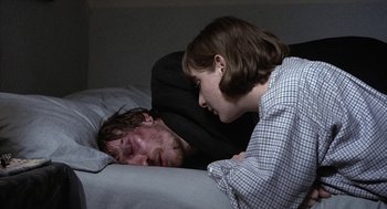 Movie still from “Naked” (1993), directed by Mike Leigh – A man and a woman laying in a bed together; Medium shot, High angle