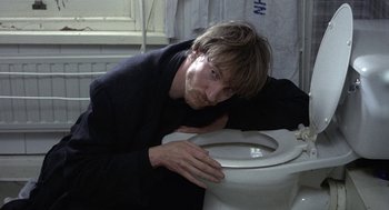 Movie still from “Naked” (1993), directed by Mike Leigh – A man leaning on the side of a toilet seat; Close Up shot, High angle