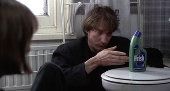 Movie still from “Naked” (1993), directed by Mike Leigh – A man sitting on the floor in front of a toilet; Close Up shot, High angle