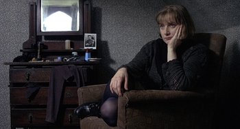 Movie still from “Naked” (1993), directed by Mike Leigh – A woman sitting in a chair in front of a mirror; Medium shot, High angle