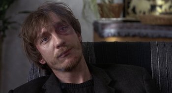 Movie still from “Naked” (1993), directed by Mike Leigh – A person sitting on a couch; Close Up shot, Over the shoulder angle