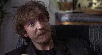 Movie still from “Naked” (1993), directed by Mike Leigh – A person sitting in a chair; Close Up shot, Over the shoulder angle