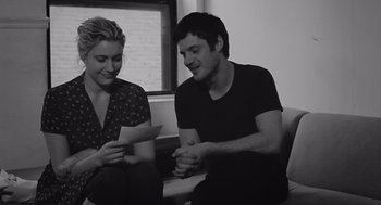 Movie still from “Frances Ha” (2012), directed by Noah Baumbach – A man and a woman sitting next to each other holding papers; Medium shot, Over the shoulder angle
