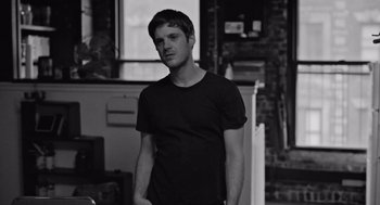 Movie still from “Frances Ha” (2012), directed by Noah Baumbach – Black and white photograph of a man in a black t - shirt; Medium shot, Low angle