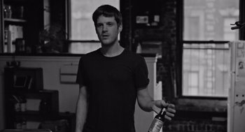 Movie still from “Frances Ha” (2012), directed by Noah Baumbach – A man holding a bottle of alcohol in his hand; Medium shot, Low angle