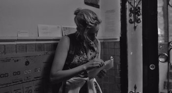 Movie still from “Frances Ha” (2012), directed by Noah Baumbach – A woman writing on a piece of paper in a room; Medium shot, Over the shoulder angle