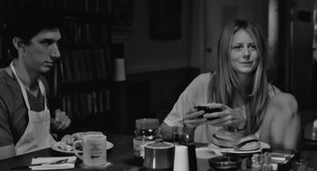 Movie still from “Frances Ha” (2012), directed by Noah Baumbach – A woman sitting at a table with a cell phone in her hand; Medium shot, Over the shoulder angle